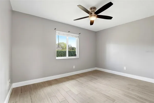 a view of empty room with wooden floor and fan
