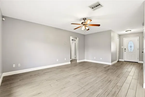 an empty room with wooden floor and a ceiling fan