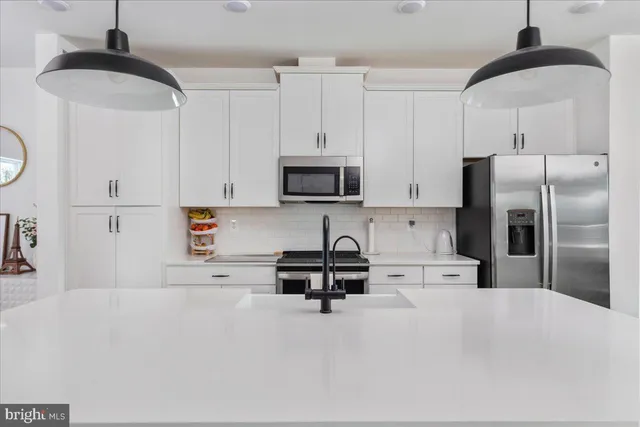 a kitchen with stainless steel appliances a refrigerator sink and white cabinets