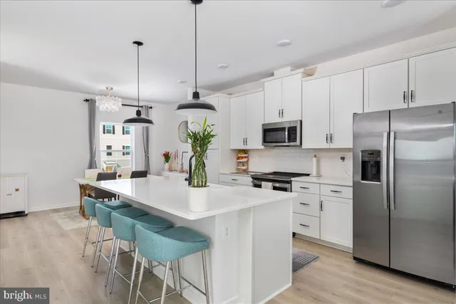 a kitchen with stainless steel appliances kitchen island granite countertop a refrigerator a stove a microwave oven a sink with island and chairs