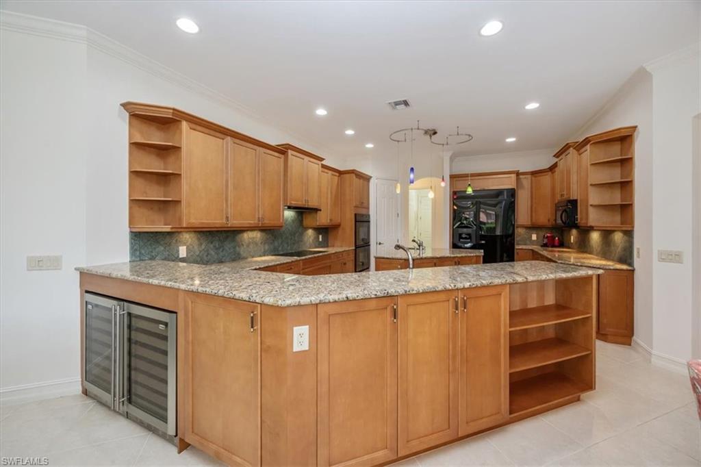 4971 Rustic Oaks Circle Naples, FL 34105 - Photo 13 of 50 a kitchen with stainless steel appliances granite countertop a sink a stove and a refrigerator