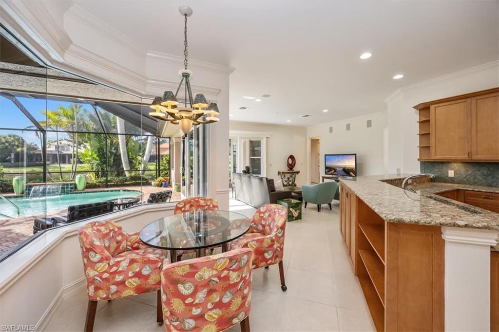 4971 Rustic Oaks Circle Naples, FL 34105 - Photo 17 of 50 a kitchen with sink refrigerator and dining table
