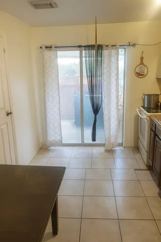 a view of a refrigerator in kitchen and an empty room in wooden floor