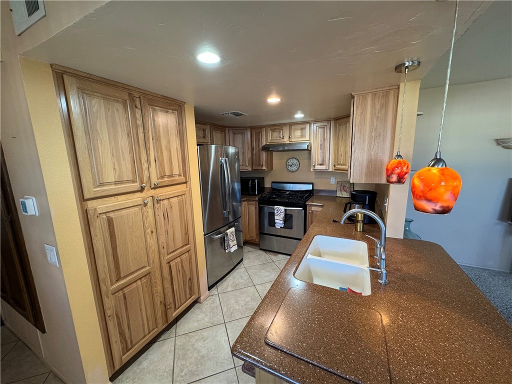 1190 Ramar Road, Unit 15 Bullhead City, AZ 86442 - Photo 5 of 17 Kitchen with appliances with stainless steel finishes, light tile patterned floors, recessed lighting, dark stone countertops, and under cabinet range hood