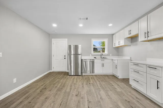 a kitchen with cabinets wooden floor and stainless steel appliances