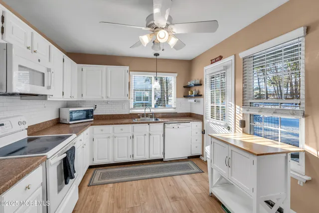 a kitchen with granite countertop a sink a counter space appliances and cabinets