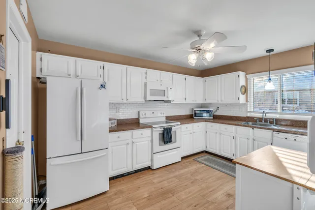 a kitchen with granite countertop white cabinets and white appliances