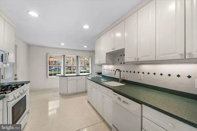 a large kitchen with stainless steel appliances granite countertop a stove and a white cabinets