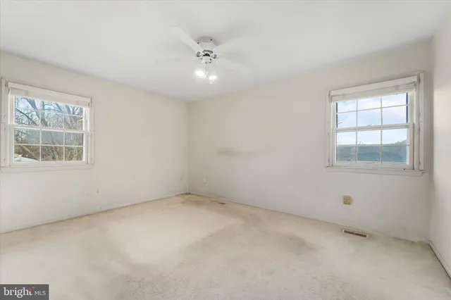 an empty room with windows and chandelier fan