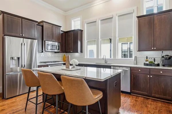 a kitchen with stainless steel appliances granite countertop a sink refrigerator stove dining table and chairs