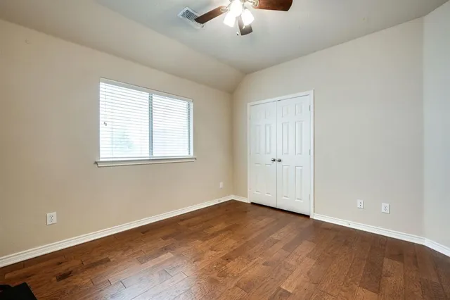 an empty room with wooden floor chandelier fan and windows