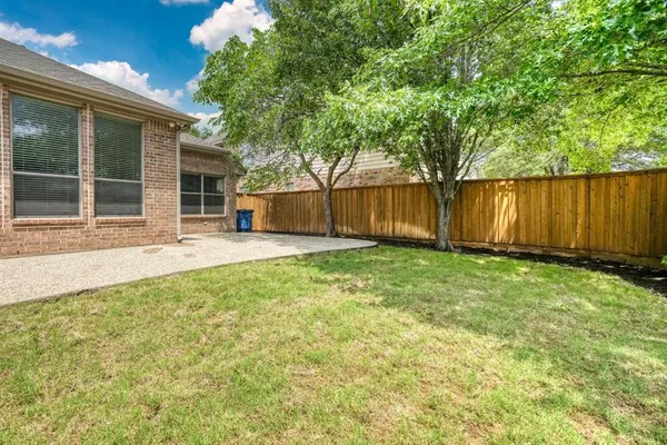 a view of a backyard with large trees and wooden fence