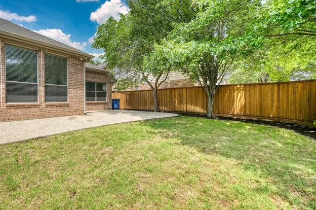 a view of a backyard with large trees and wooden fence