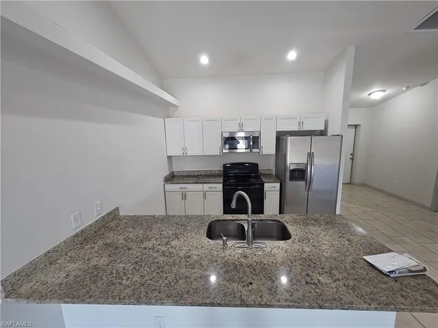 a kitchen with stainless steel appliances kitchen island a stove a refrigerator and a sink