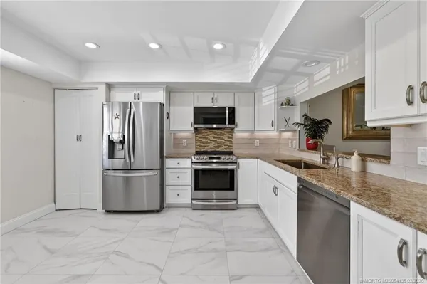 a large kitchen with stainless steel appliances granite countertop a stove a sink and a refrigerator