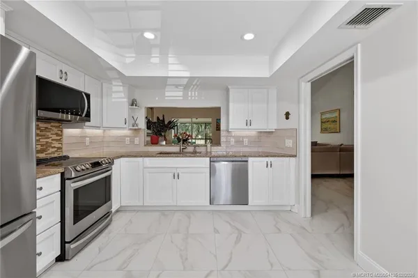 a kitchen with granite countertop a sink a counter top space stainless steel appliances and cabinets