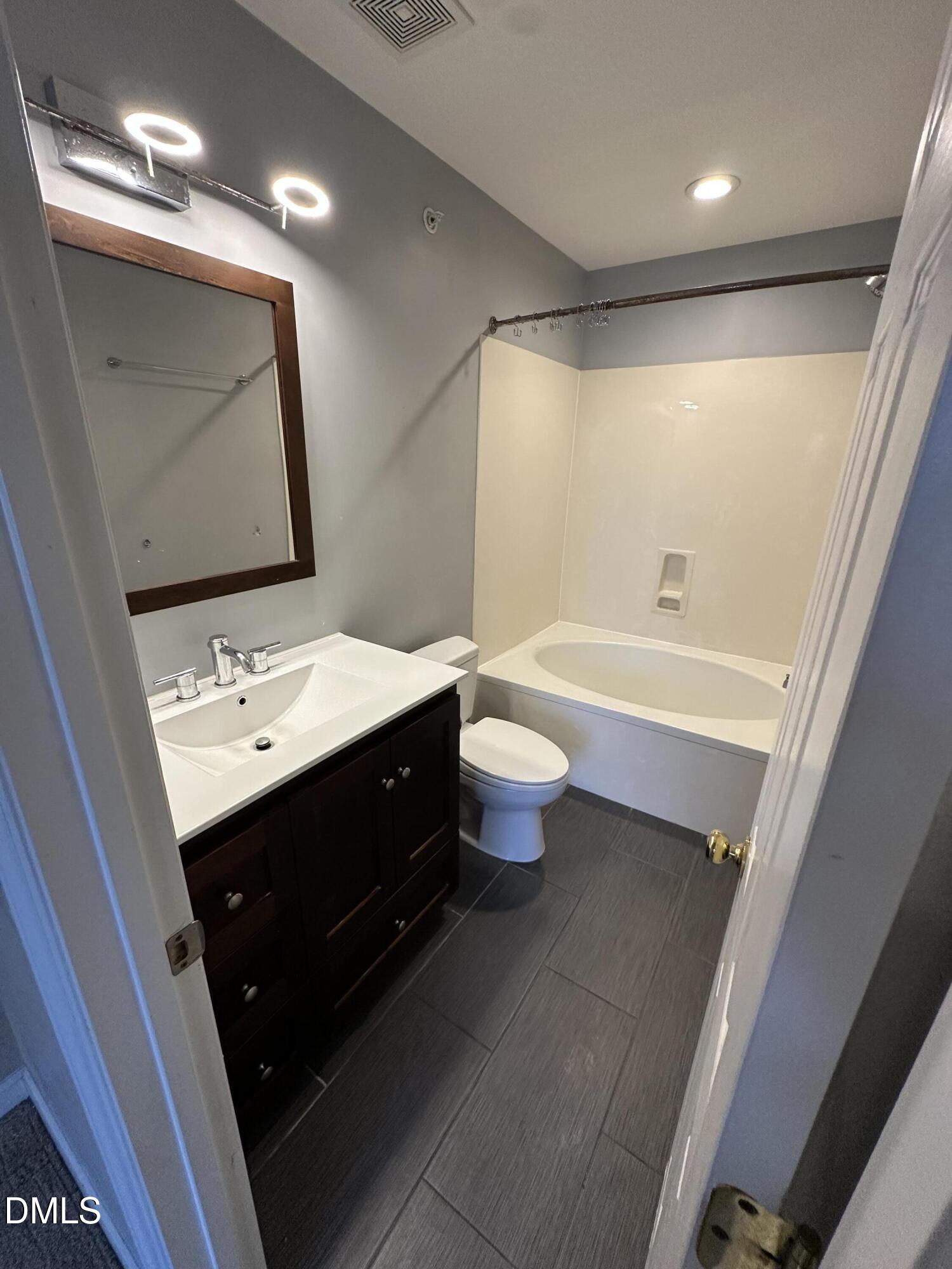 1901 Trailwood Heights Lane, Unit 302 Raleigh, NC 27603 - Photo 10 of 16 a bathroom with a double vanity sink toilet mirror and bathtub