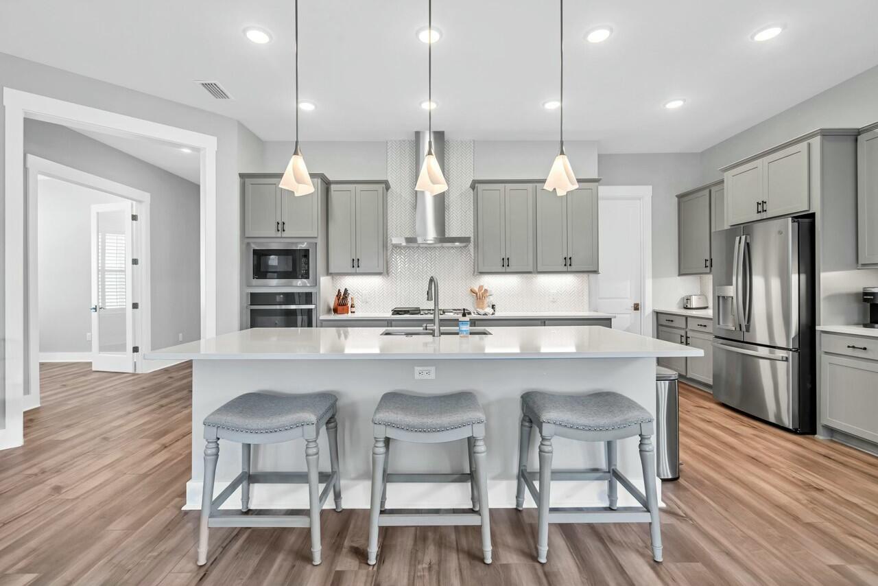 117 River Rise Way Watersound, FL 32461 - Photo 3 of 14 a kitchen with stainless steel appliances granite countertop a table chairs stove microwave and cabinets