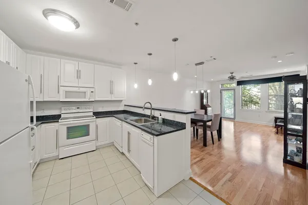 a kitchen with stainless steel appliances granite countertop a stove top oven a sink with white cabinets and wooden floor