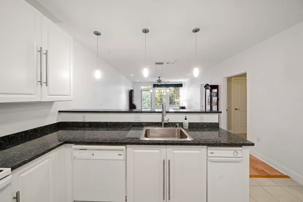 a kitchen with granite countertop a sink stainless steel appliances white cabinets and a granite counter tops