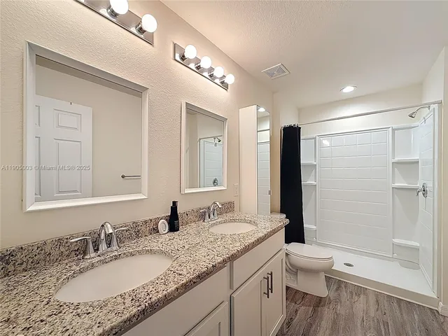 a bathroom with a granite countertop sink toilet and shower