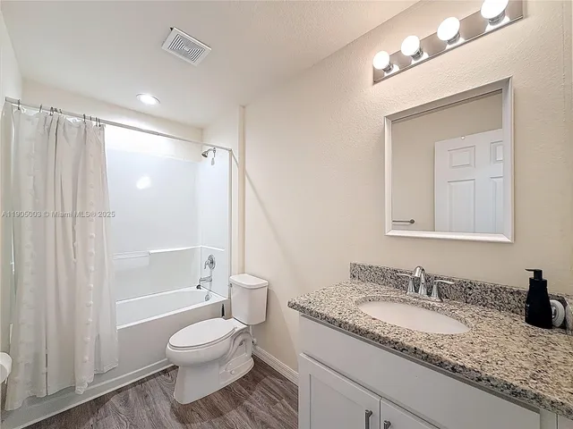 a bathroom with a granite countertop sink mirror vanity and toilet