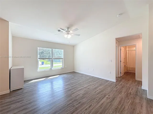 a view of an empty room with a window and wooden floor