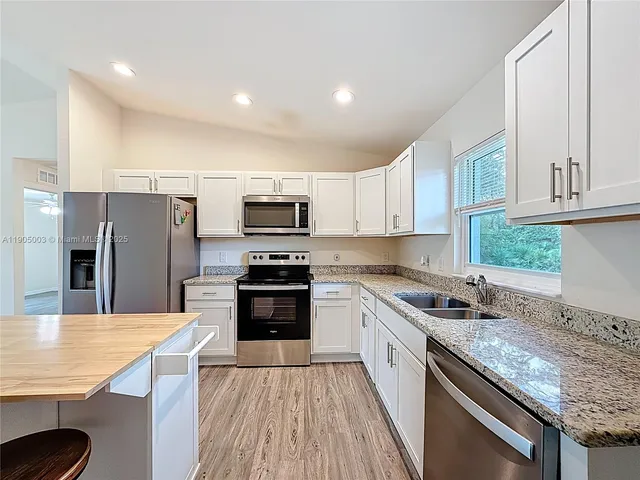 a kitchen with stainless steel appliances granite countertop a kitchen island hardwood floor sink and stove