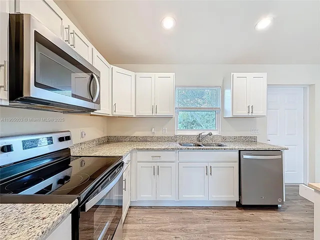 a kitchen with stainless steel appliances granite countertop a stove a sink dishwasher and a microwave oven with wooden cabinets