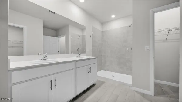 a spacious bathroom with a double vanity sink a mirror and a shower