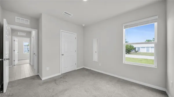 a view of an empty room with closet and a window