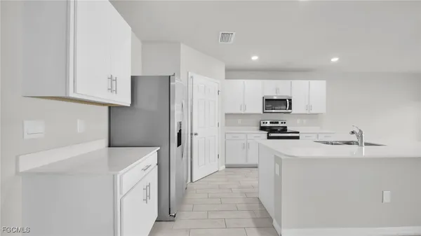 a kitchen with stainless steel appliances a refrigerator sink and white cabinets