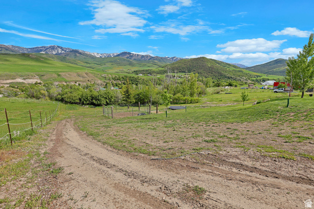 306 Spring Road Preston, ID 83263 - Photo 45 of 55 Expansive rural property featuring an unpaved access road, partial fencing, varied topography, mature trees, and distant snow-capped mountains