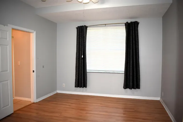 an empty room with wooden floor and windows