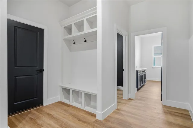 a view of an empty room with wooden floor and a bathroom