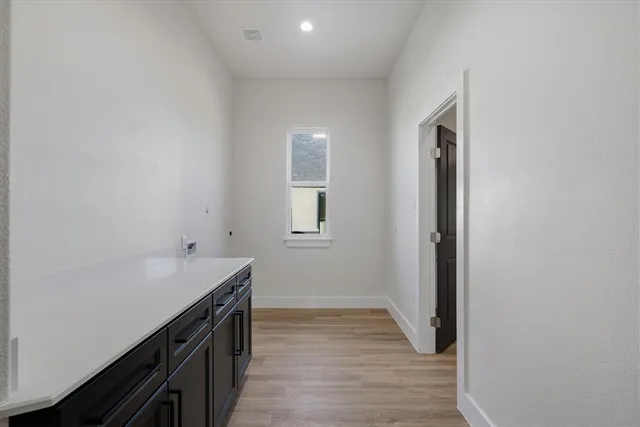 an empty room with wooden floor chandelier and windows