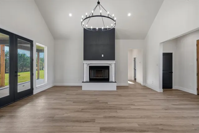 a view of an empty room with wooden floor fireplace and a window