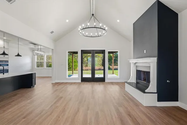 a view of an empty room with wooden floor fireplace and a window