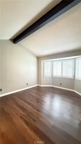 a view of an empty room with a window and hardwood floor