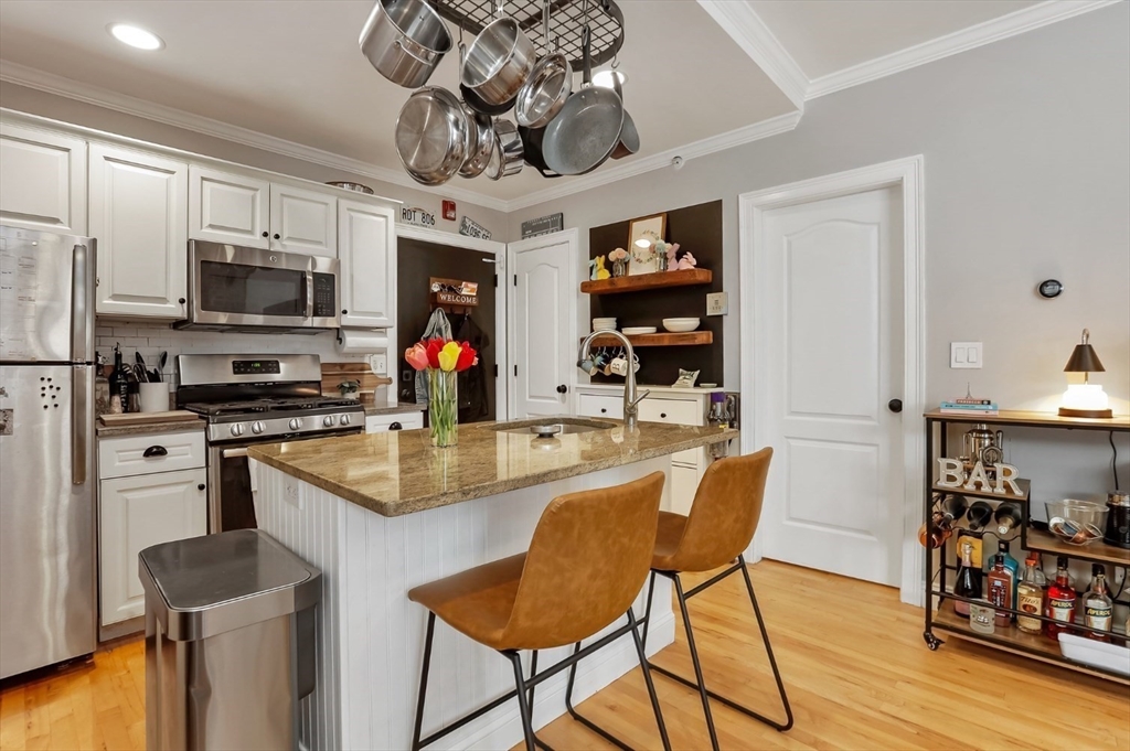 454 Hanover Street, Unit 4 Boston, MA 02113 - Photo 7 of 23 a kitchen with stainless steel appliances granite countertop a sink dishwasher a microwave oven a stove with wooden floor and cabinets