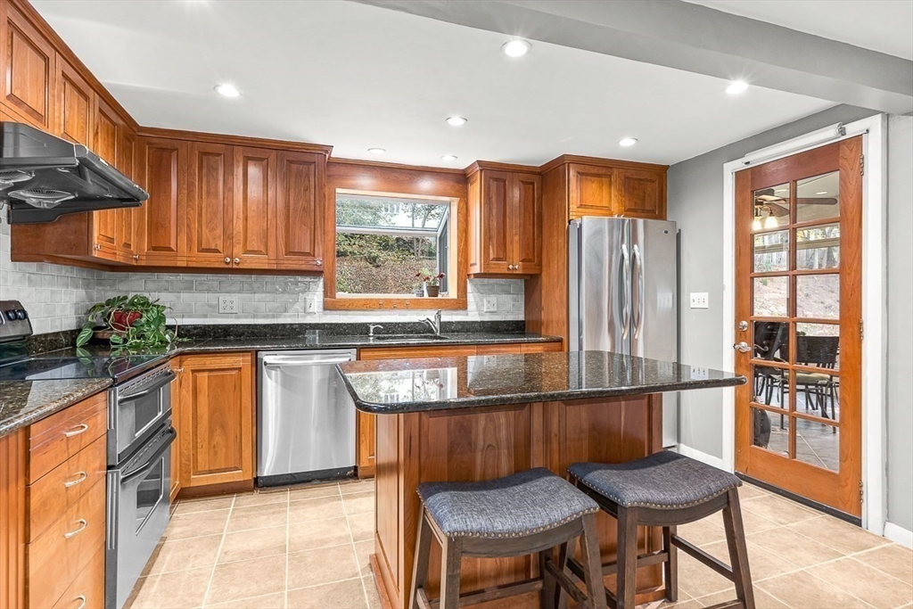 6 Marchant Road Winchester, MA 01890 - Photo 11 of 42 a kitchen with stainless steel appliances granite countertop wooden cabinets a dining table and chairs