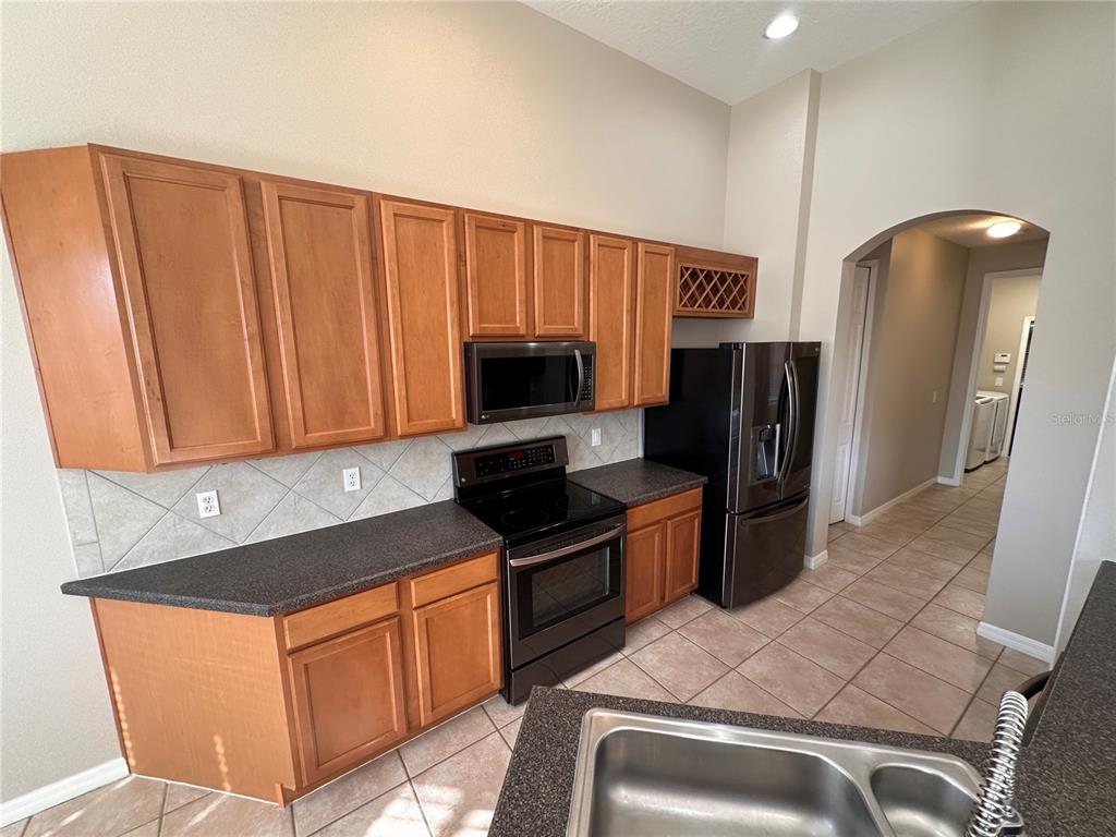 4962 Rock Rose Loop Sanford, FL 32771 - Photo 8 of 27 a kitchen with granite countertop a refrigerator stove and microwave