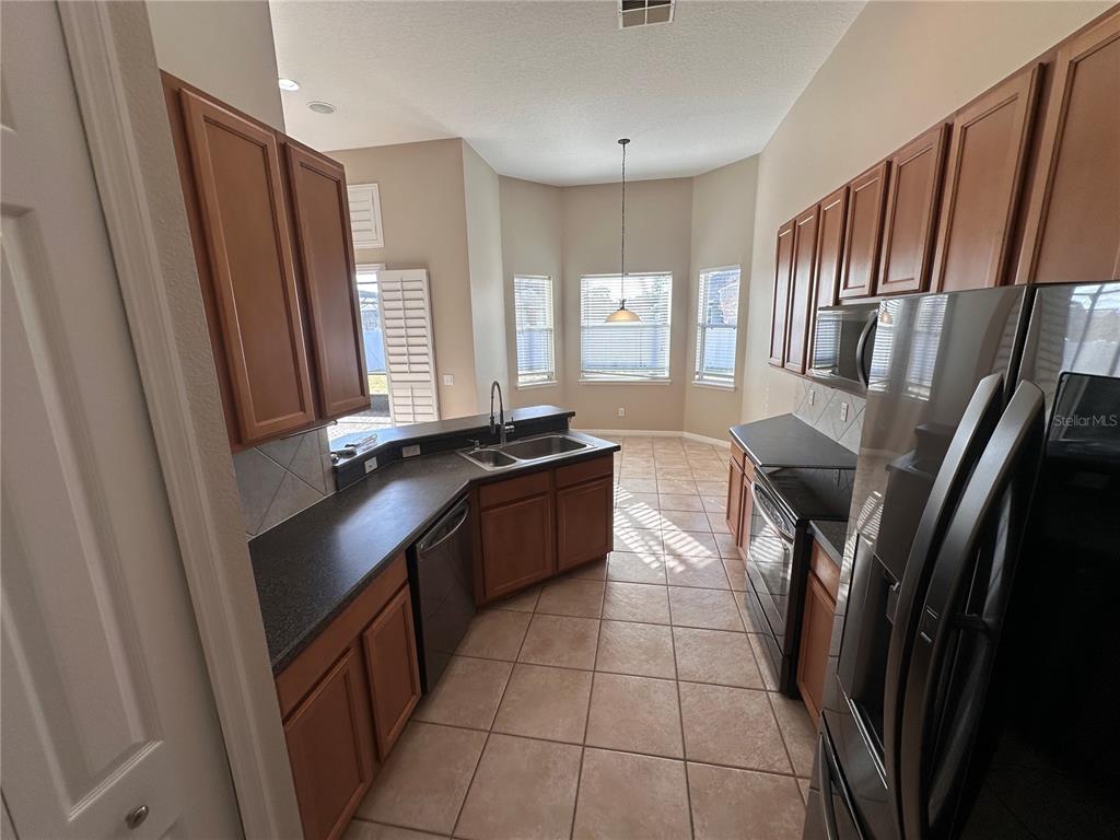 4962 Rock Rose Loop Sanford, FL 32771 - Photo 10 of 27 a kitchen with granite countertop a refrigerator a sink a stove and cabinets