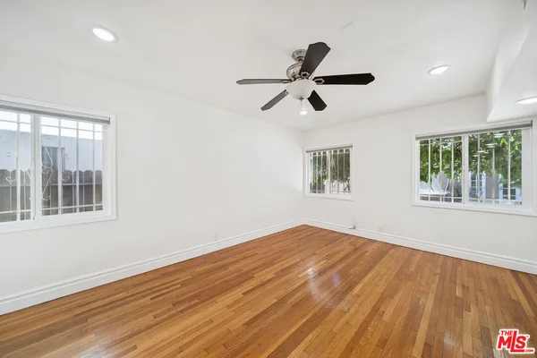 a view of empty room with wooden floor and fan