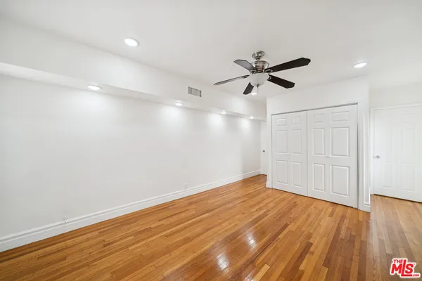 an empty room with wooden floor and a ceiling fan