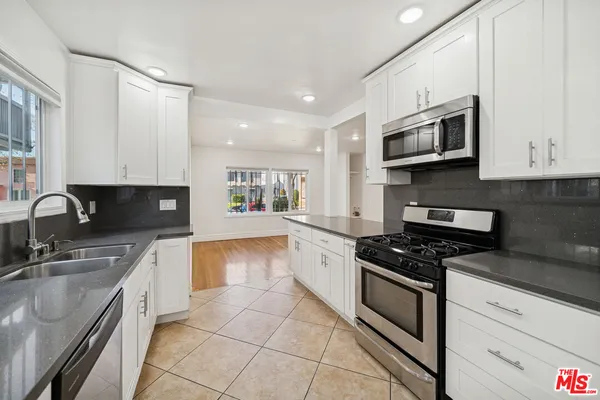 a kitchen with stainless steel appliances granite countertop a sink a stove top oven a granite counter space and cabinets
