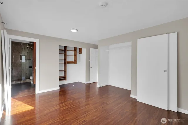 a view of an empty room with wooden floor and closet
