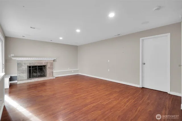 a view of empty room with wooden floor and fireplace