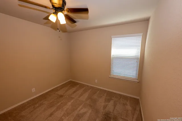 an empty room with a window and a fan