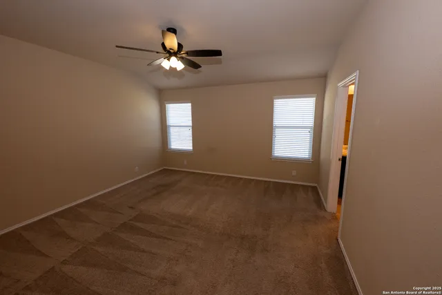 en empty room with windows and ceiling fan